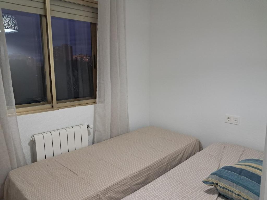 two beds in a room with a window at Apartamento CABO HUERTAS in Alicante