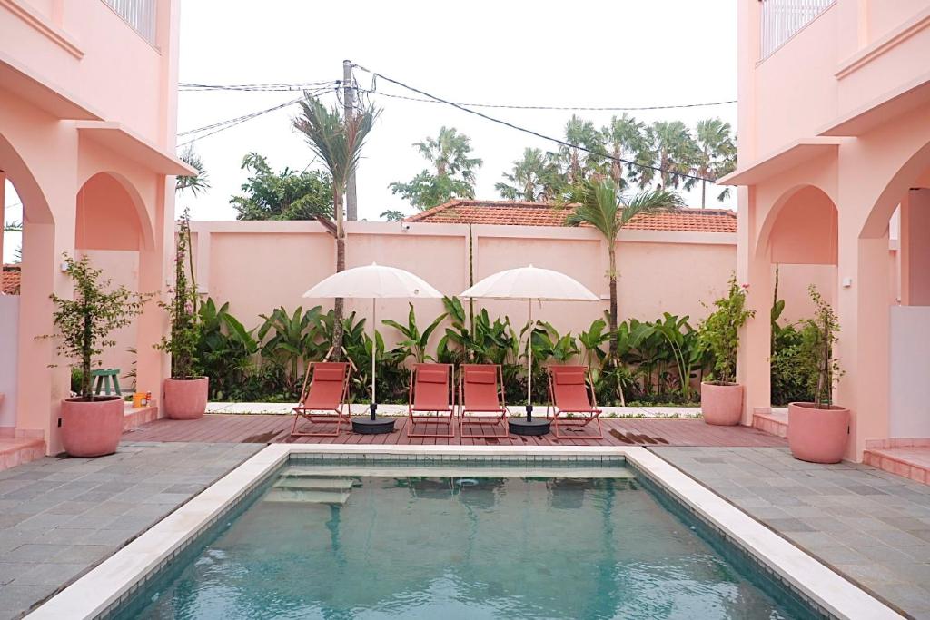 a swimming pool in a building with chairs and umbrellas at Ponder Bali Canggu in Canggu