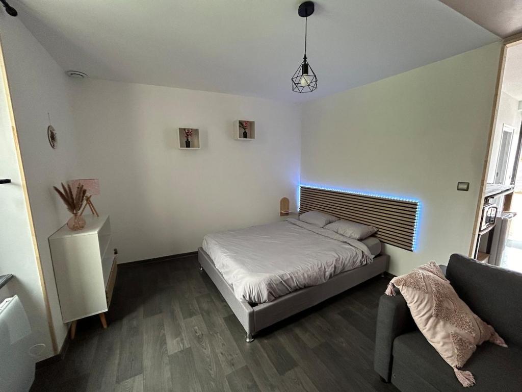 un dormitorio con una cama y un sofá en Studio indépendant, en Saint-Éloi
