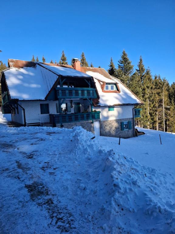una casa nella neve con un mucchio di neve di Apartma Jurček Rogla a Rakovec