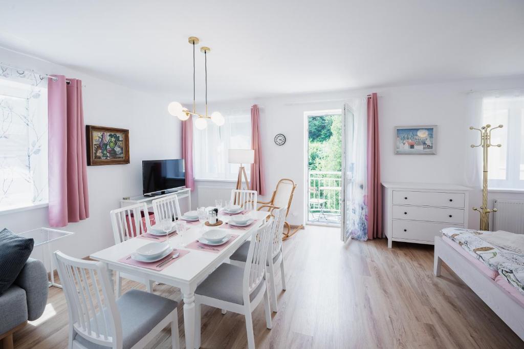 una sala da pranzo bianca con tavolo e sedie di Proton apartment a Jáchymov