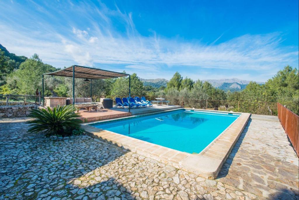 a swimming pool in a backyard with a patio at Can Guillo in Pollença
