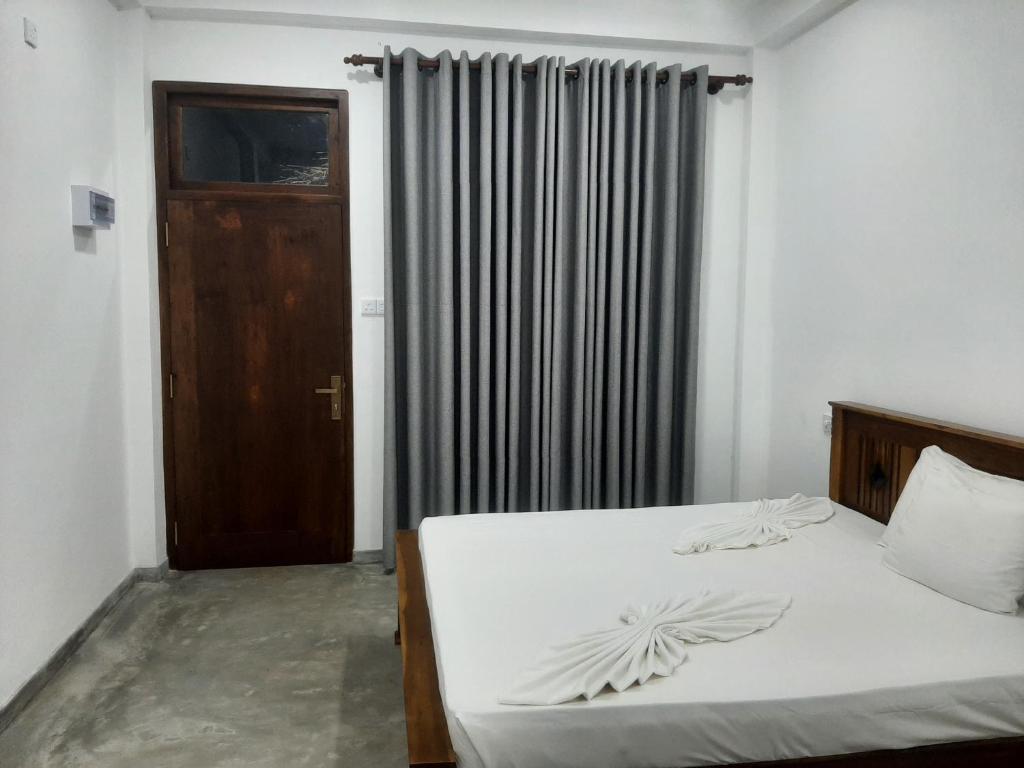 1 dormitorio con 1 cama con sábanas blancas y puerta en Kusum Family House, en Dikwella