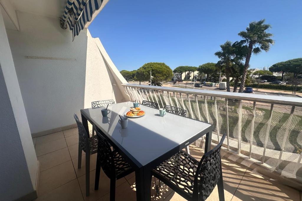 d'une table et de chaises sur un balcon avec vue sur la rue. dans l'établissement La Goélette - Appartement une chambre avec terrasse proche de la mer, au Grau-du-Roi