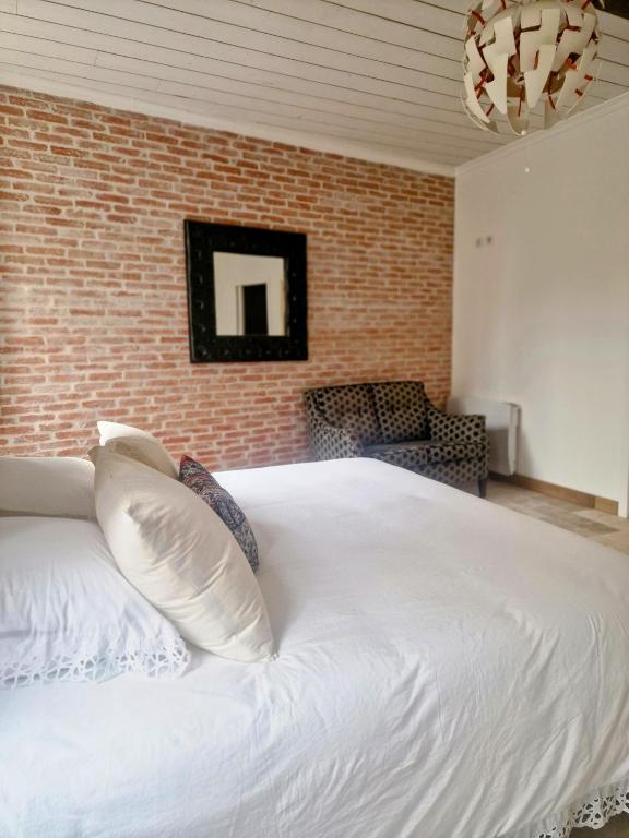 une chambre avec un lit blanc et un mur de briques dans l'établissement Le 23 Maison Silva, à Blaye