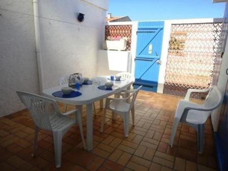 une cuisine avec une table et des chaises ainsi qu'une porte bleue dans l'établissement Maison 3 pièces PORT LA NOUVELLE PN500-005, à Port-la-Nouvelle