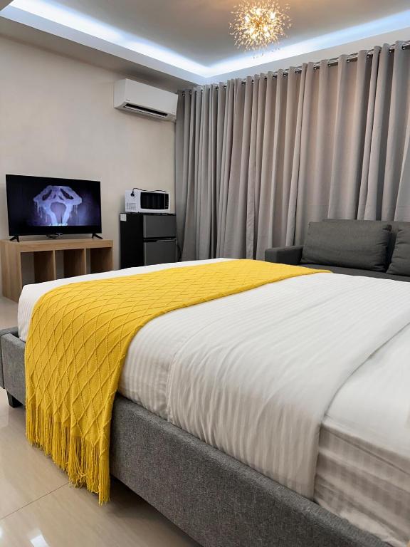 ein Schlafzimmer mit einem großen Bett mit einer gelben Decke in der Unterkunft Guestroom 2 -3rd flr Barretto, Olongapo near beach in Olongapo
