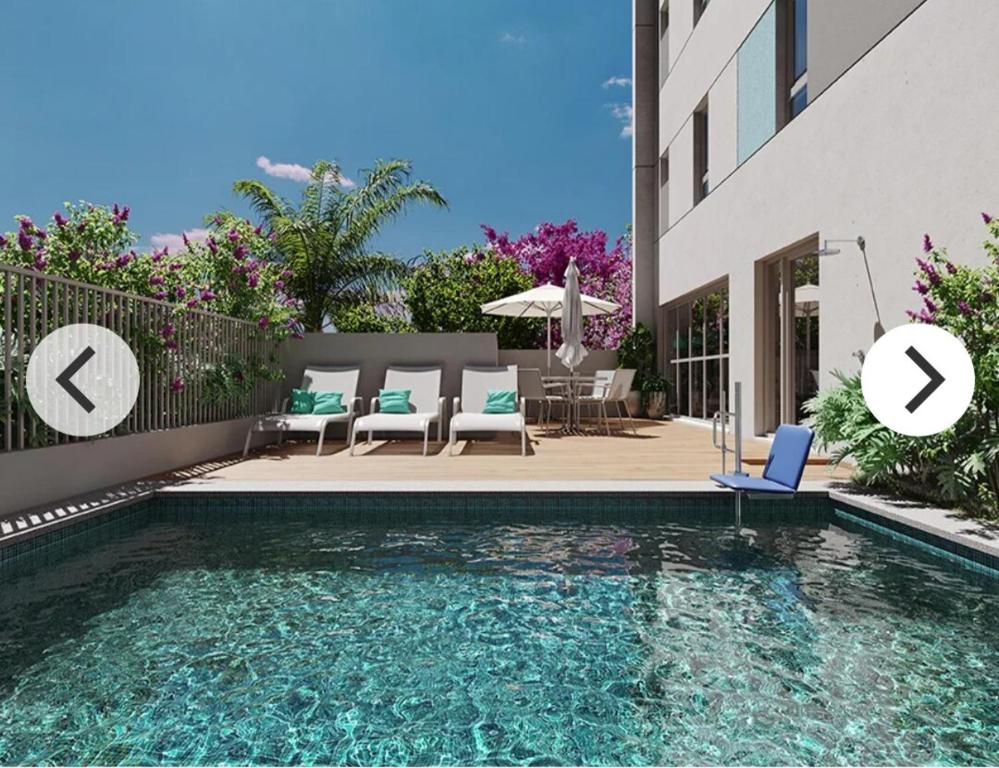 - une piscine avec des chaises et une table dans l'établissement Studio Aconchegante para 2 pessoas, à São Paulo