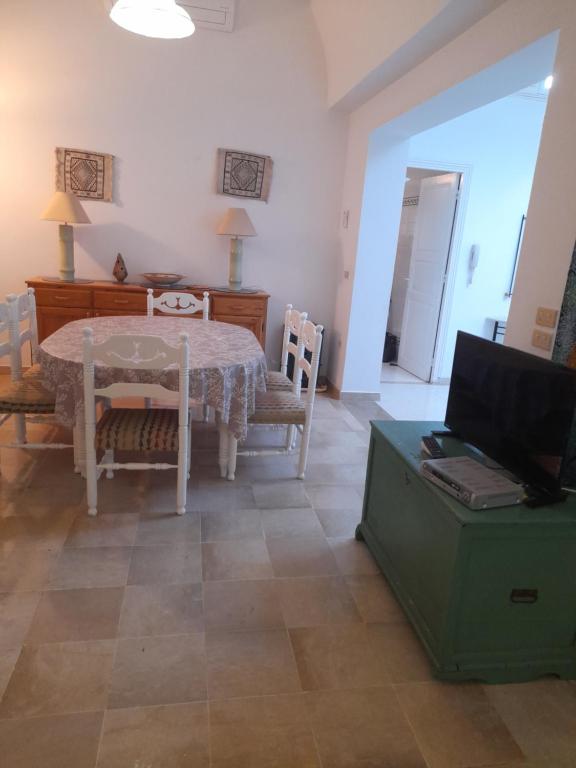 un soggiorno con tavolo, sedie e televisione di Villa meublée à Monastir wifi illimité a Monastir