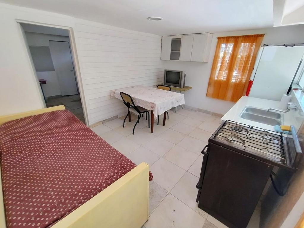 a small room with a table and a small kitchen at Casa para 3 personas con patio in Barrio Félix U Camet