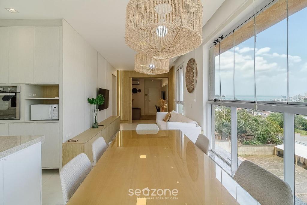 a living room with a table and a large window at Apartamento c/ Churrasqueira 240m da Praia EHI0401 in Praia Brava