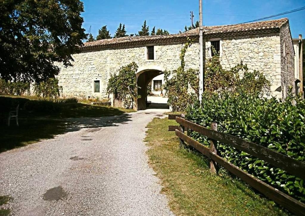 un bâtiment en pierre avec un portail et une route dans l'établissement Gite le Sagnac 10 personnes, à Sauzet
