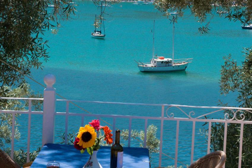 - une table avec une bouteille de vin et un bateau dans l'eau dans l'établissement Ilios Hotel & Villas, à Yénion