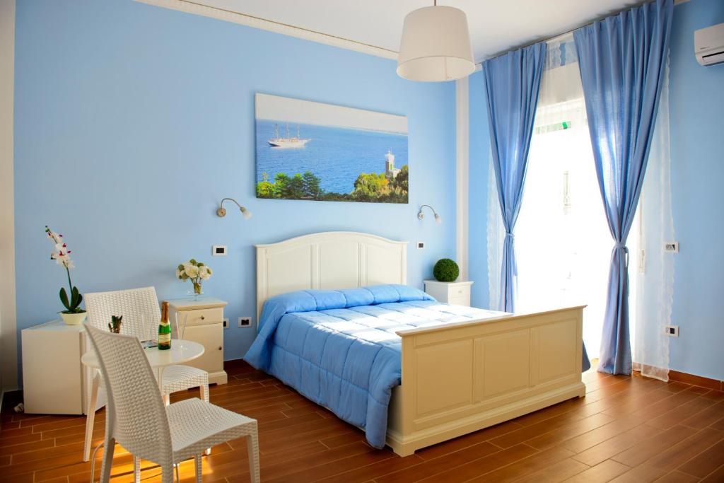 1 dormitorio azul con 1 cama, mesa y sillas en I Delfini, en Agropoli