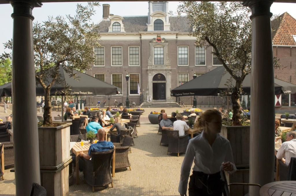a group of people sitting at tables in front of a building at l'Auberge Damhotel in Edam