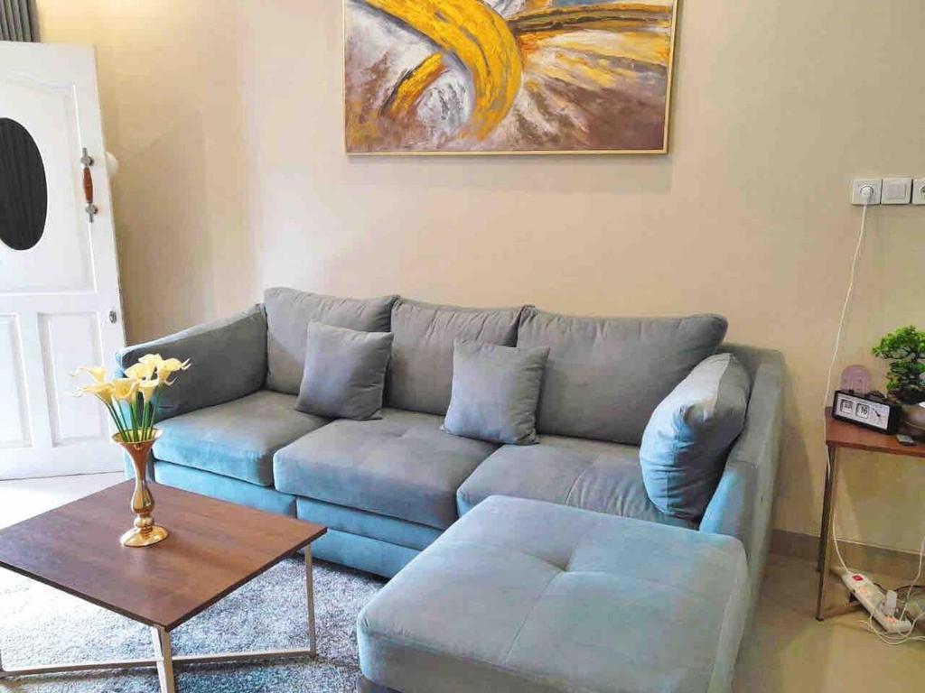 a living room with a blue couch and a table at Home villa minimalist 5 minute from toll gate in Parungkuda