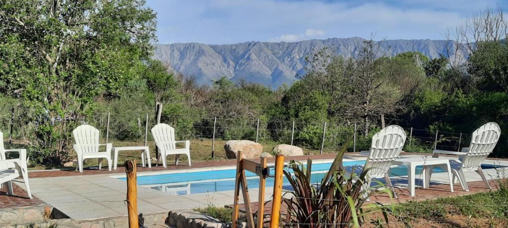 a group of white chairs and a table and a pool at Cabañas Paraje Noviembre in Nono
