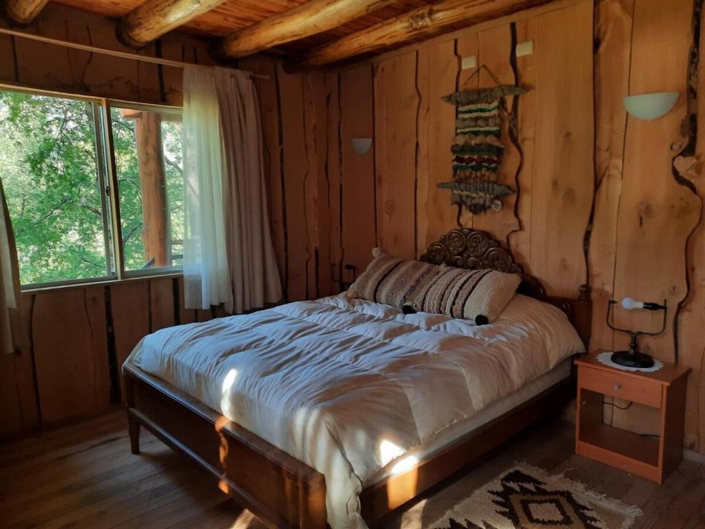a bedroom with a bed in a log cabin at Cabaña en Parcela con Tinaja in Trancura
