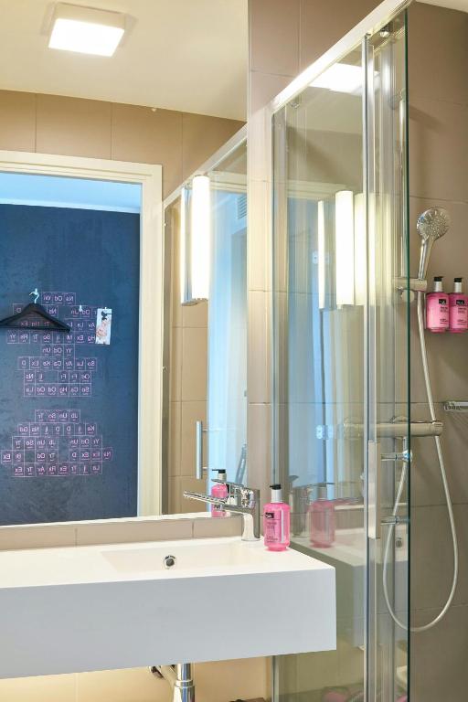 a bathroom with a shower and a sink and a mirror at Moxy Aberdeen Airport in Dyce