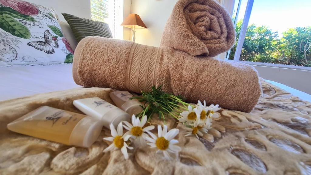 un asciugamano arrotolato e fiori su un letto di Fun at Beach a Kenton-on-Sea