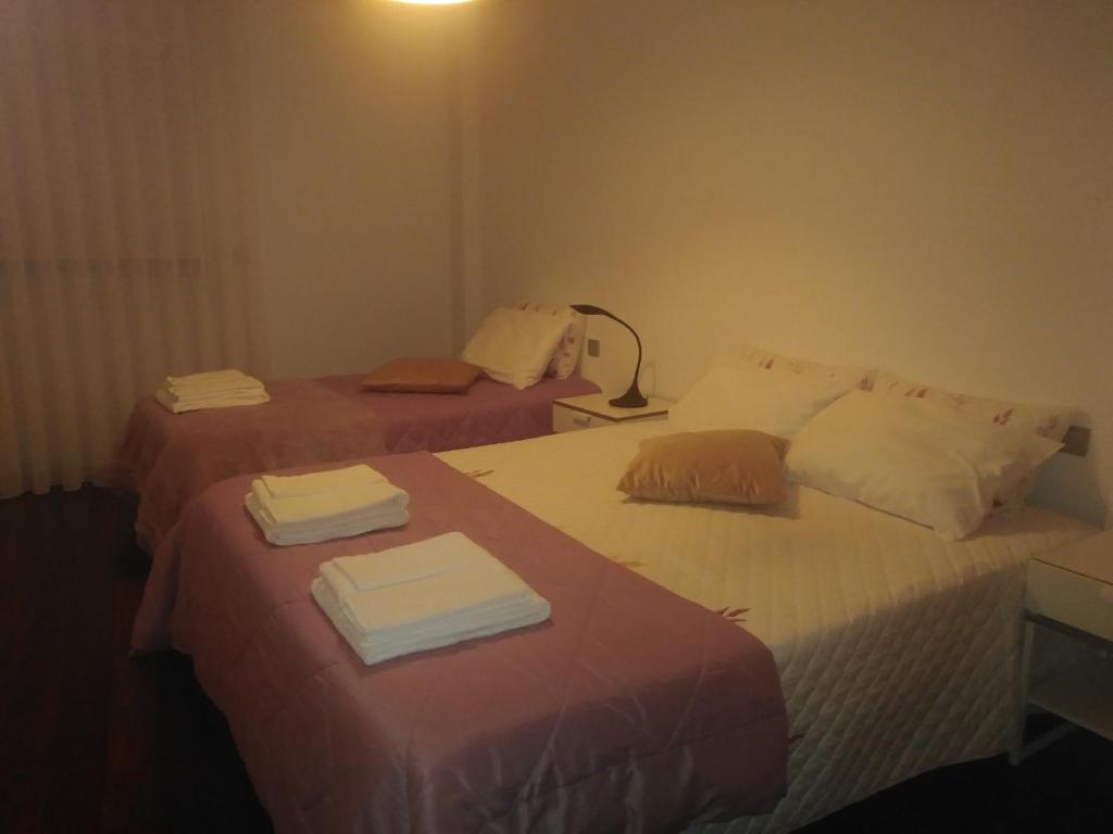 two beds in a hotel room with towels on them at AL Mirador in Aveiro
