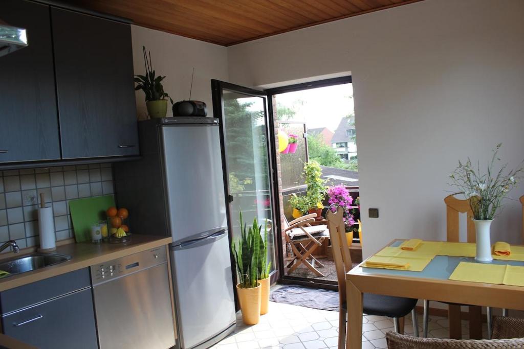Una cocina con refrigerador de acero inoxidable y una mesa. en Sunshine-Flat Düsseldorf-Ratingen, en Ratingen