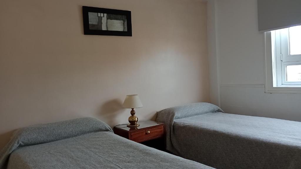 a room with two beds and a lamp on a table at Hotel Centro Naval in Buenos Aires