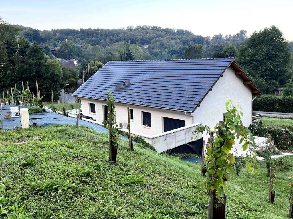 une maison blanche avec un toit noir sur une colline dans l'établissement villa du lac, à Aiguebelette-le-Lac