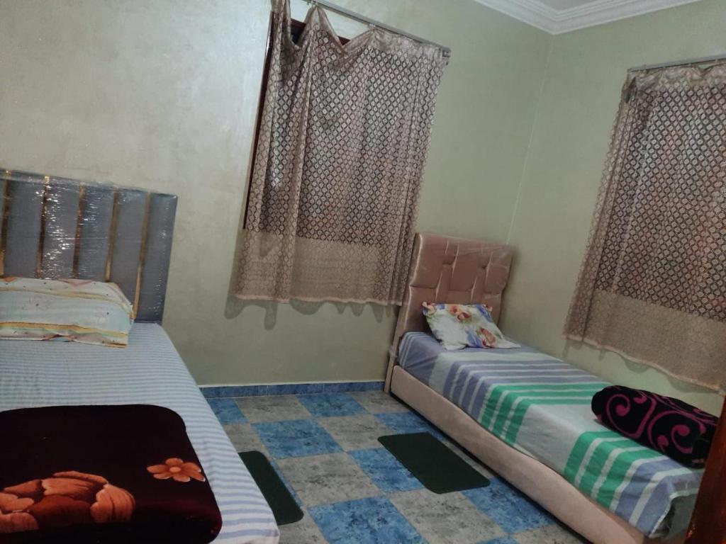 Un dormitorio con dos camas y dos ventanas. en Alkaoutar, en Sidi Ifni