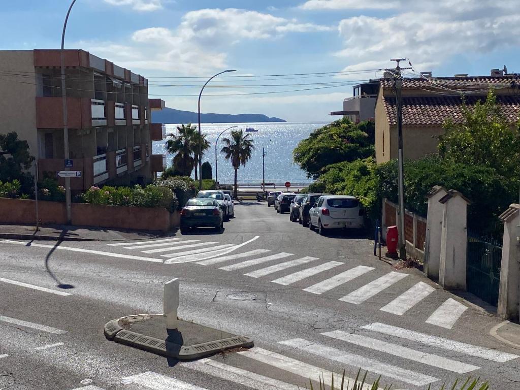 une rue avec des voitures garées sur le bord de la route dans l'établissement Le Paradis Bleu, à Cavalaire-sur-Mer