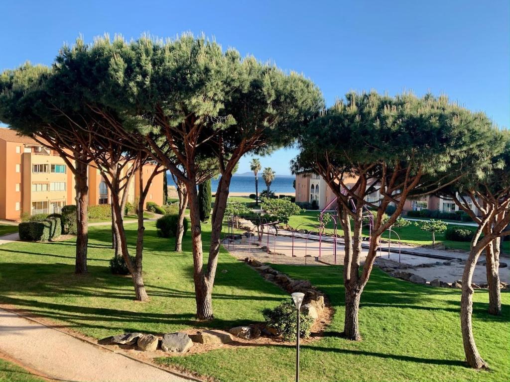 un groupe d'arbres dans un parc à côté d'un trottoir dans l'établissement L Eden Croisette nid douillet en bord de plage, à La Londe-les-Maures