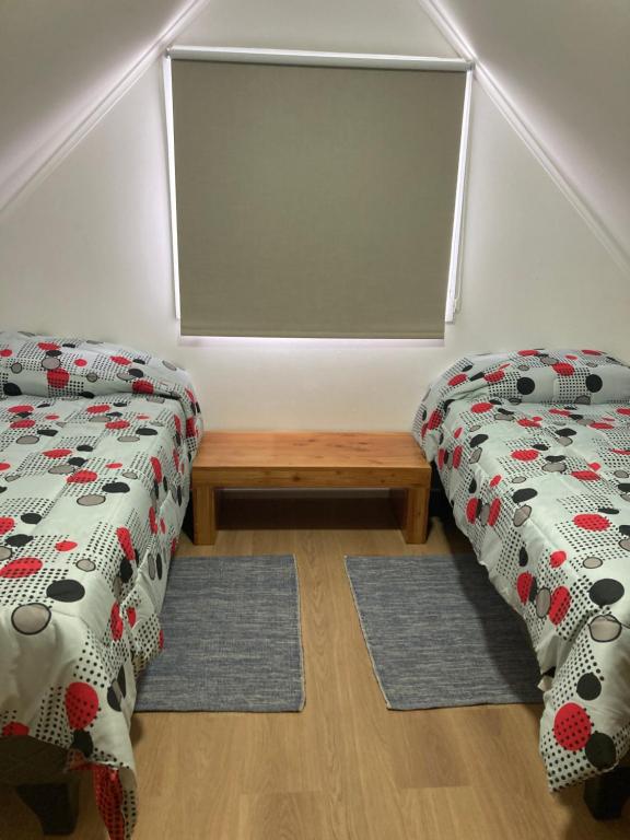 a room with two twin beds and a bench at Casa Relmu in Puerto Varas