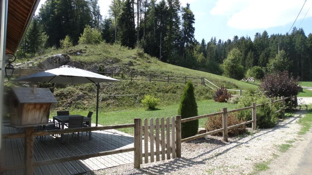 une terrasse en bois avec un parasol et une chaise dans l'établissement Maison au cœur de la forêt, à Saint-Laurent-en-Grandvaux