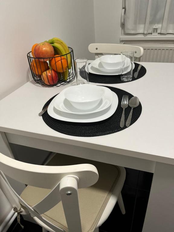 a table with two plates and a basket of fruit at Stan na dan Pozarevac Apartman Olja in Požarevac
