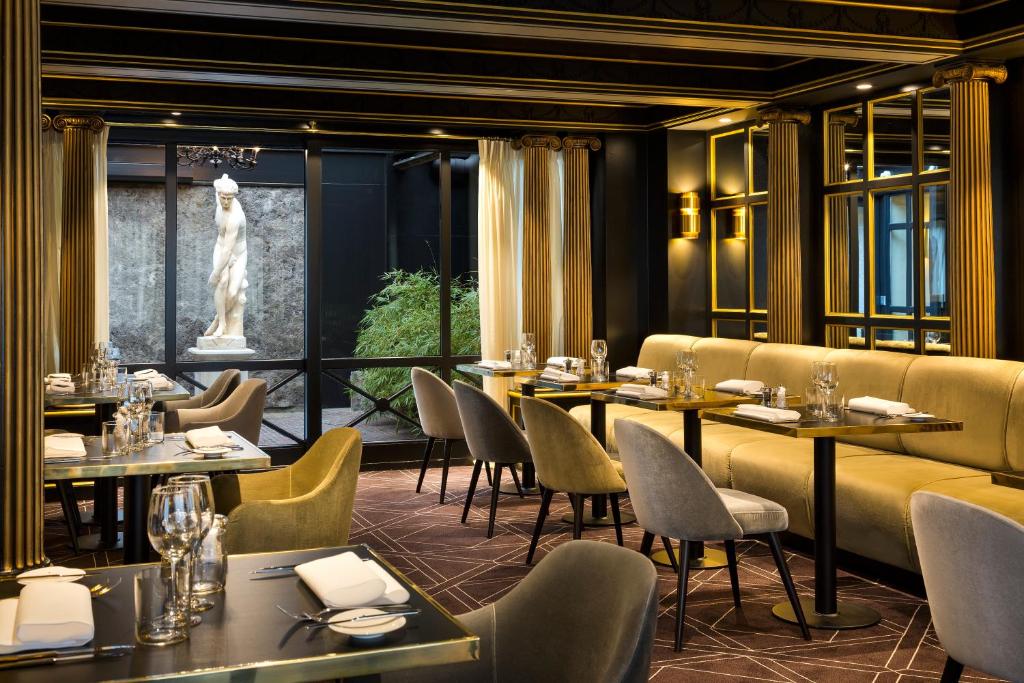 a restaurant with tables and chairs and a statue at Hotel Barsey by Warwick in Brussels
