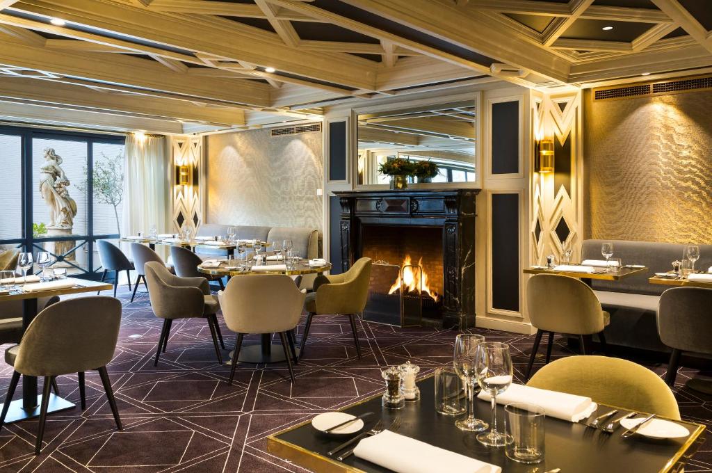 a restaurant with tables and chairs and a fireplace at Hotel Barsey by Warwick in Brussels