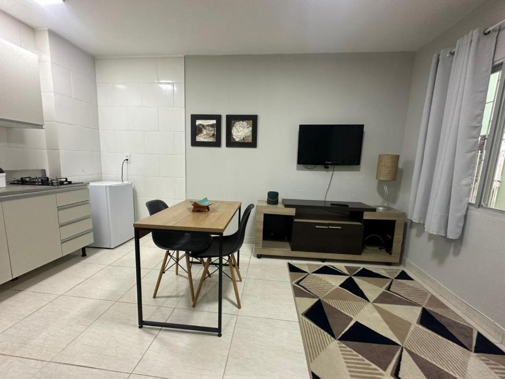 a kitchen with a table and a tv in a room at Studio no coracao do Kobrasol in São José