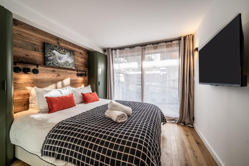 een slaapkamer met een bed en een flatscreen-tv bij Rosalia Alpina 3 Chambres in Morzine
