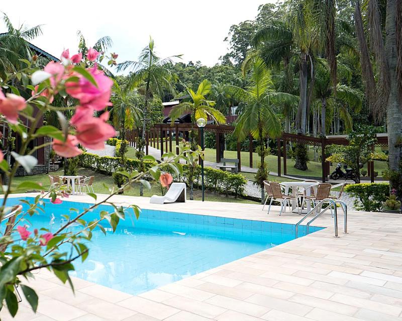 a man working on a laptop next to a swimming pool at Quinta Da Bica D'Agua Village in Florianópolis