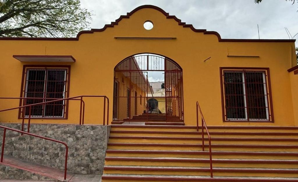 a yellow building with stairs in front of it at La Gran Manzana in Tizimín