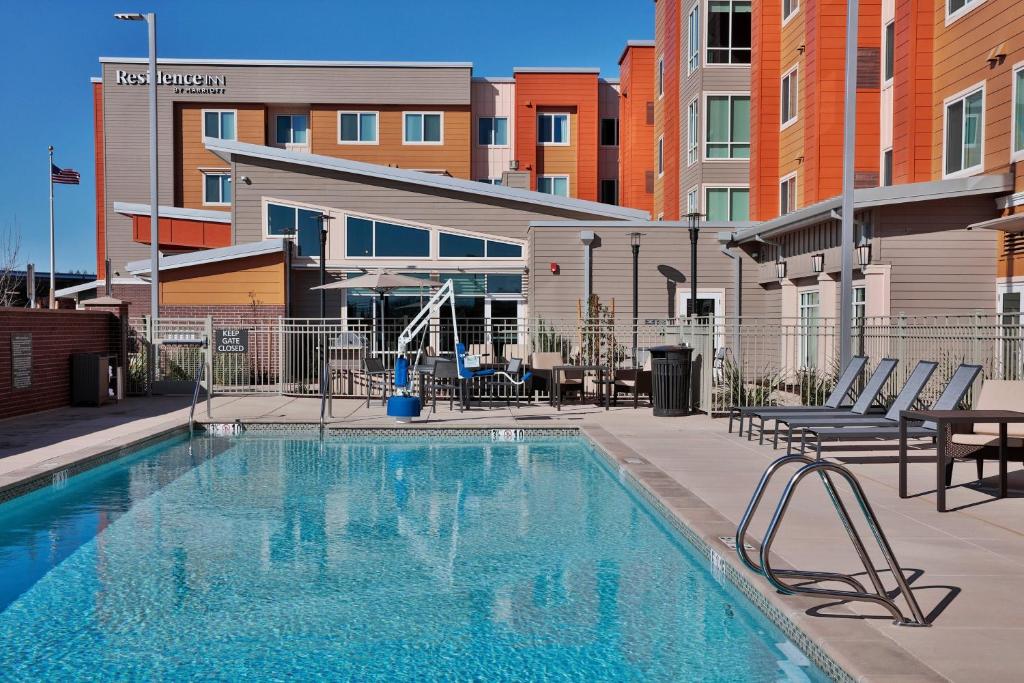 a large swimming pool with chairs and a building at Residence Inn Sacramento Davis in Davis