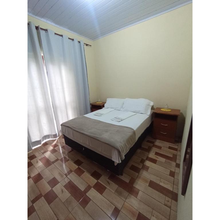 a small bedroom with a bed and a window at Flor da serra in Santo Antônio do Pinhal