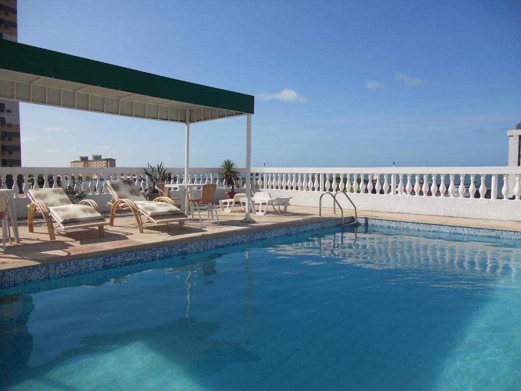 a swimming pool with chairs and tables and a building at Algarve Praia Hotel in Fortaleza