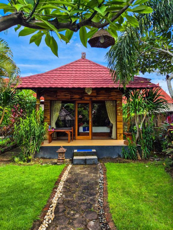 a small house with a red roof in a yard at Wadon Menjangan homestay in Banyuwedang
