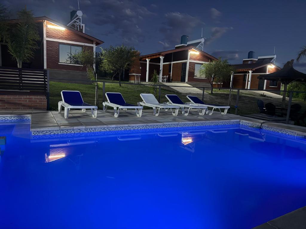 een groep stoelen naast een zwembad in de nacht bij Cabañas AdamiS in Villa Cura Brochero