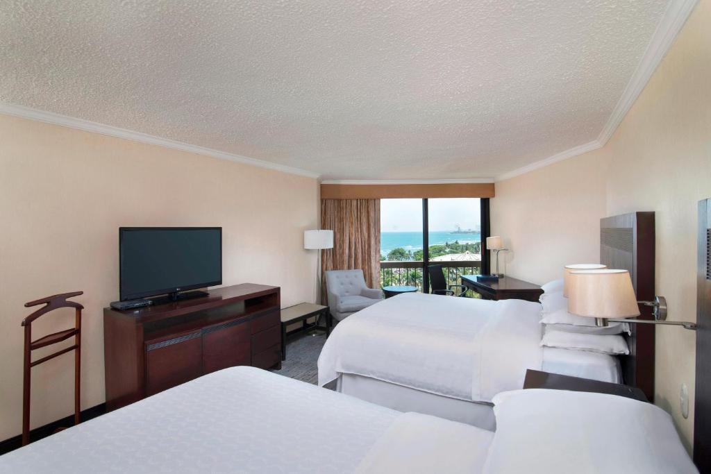 a hotel room with two beds and a flat screen tv at Sheraton Santo Domingo in Santo Domingo