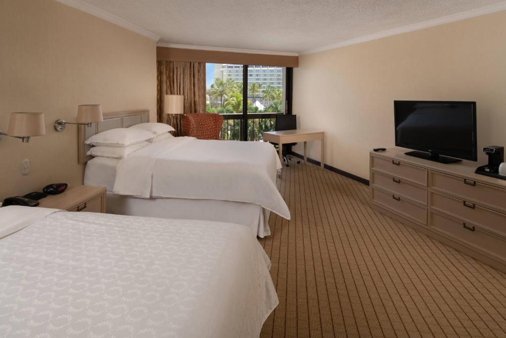 a hotel room with three beds and a flat screen tv at Sheraton Santo Domingo in Santo Domingo