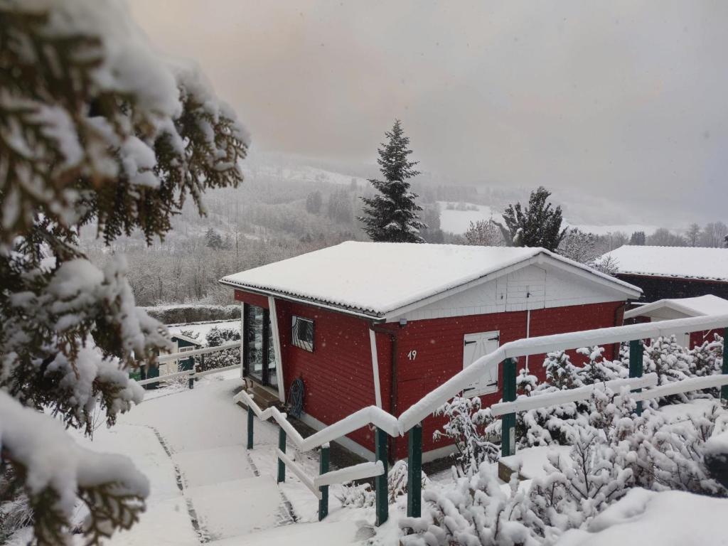 un edificio rojo cubierto de nieve con una valla en Ferienhaus Bergblick Urlaub mit Hund, en Meschede