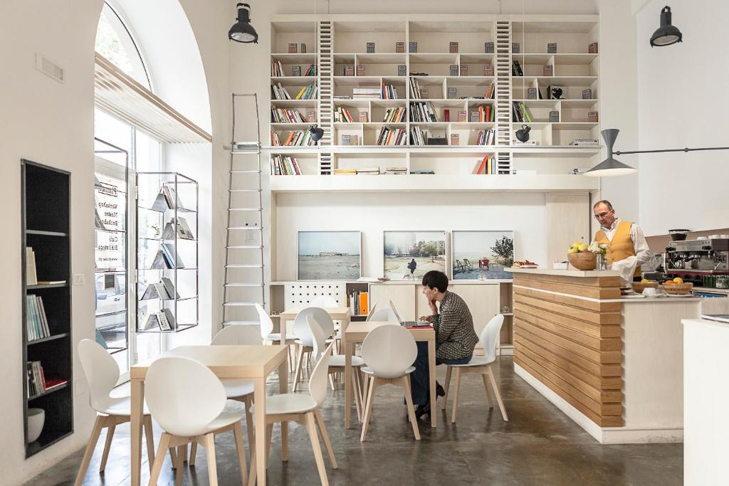 una cucina e una sala da pranzo con sedie bianche e tavolo di Imago Plus Hotel a Bari