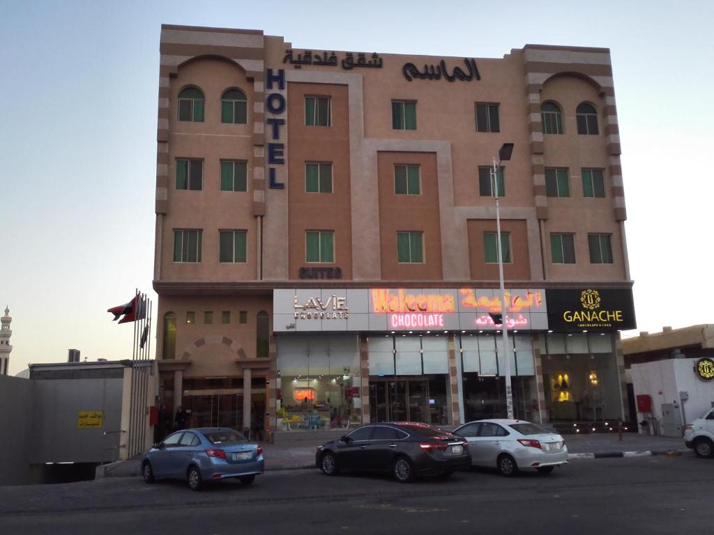 un gran edificio con coches estacionados en un estacionamiento en Al Masem Luxury Hotel Suite 5, en Al Hofuf